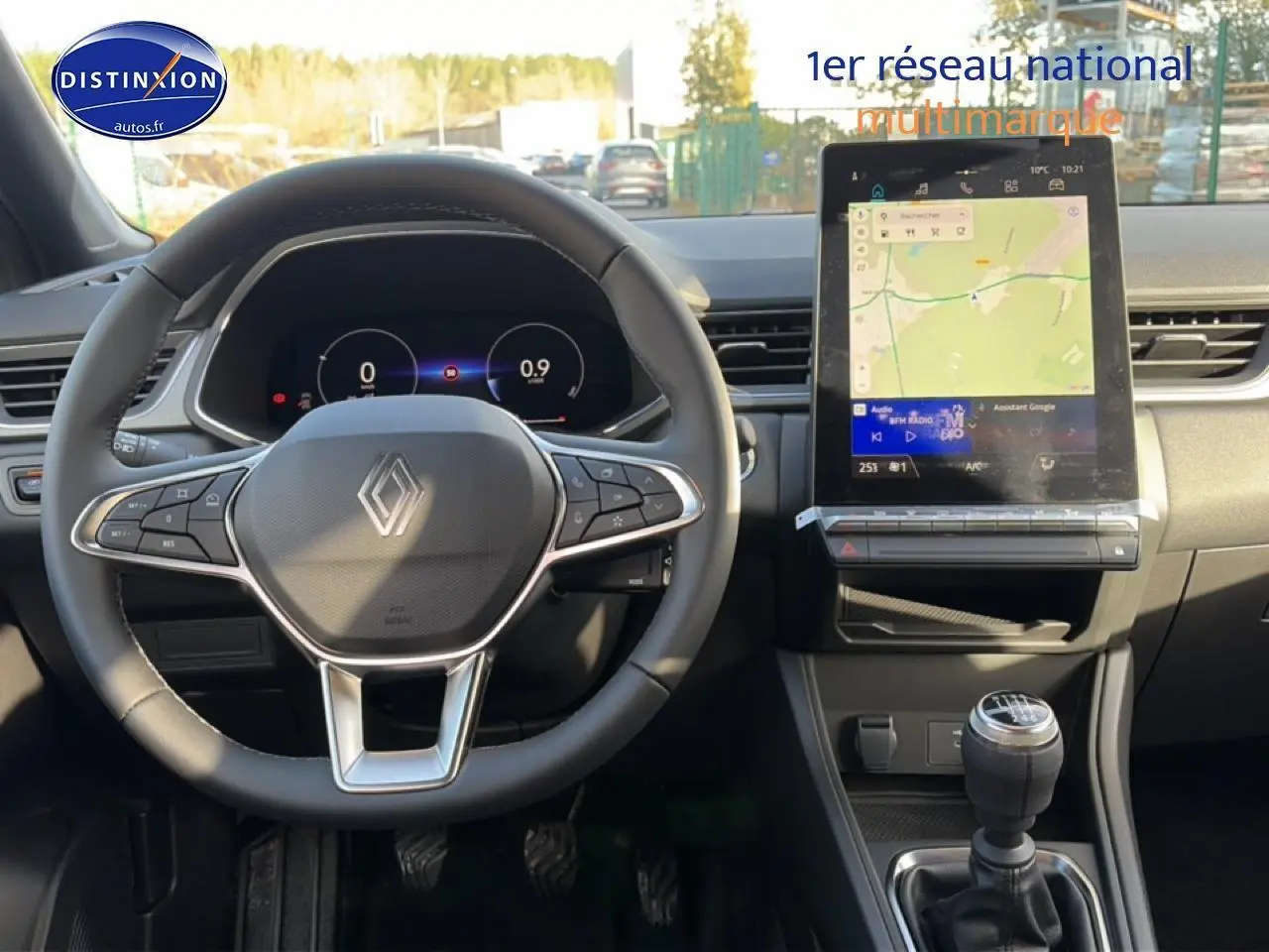 Vue intérieure avant du tableau de bord du Renault Captur bleu iron 2025 avec volant multifonction et écran tactile vertical.