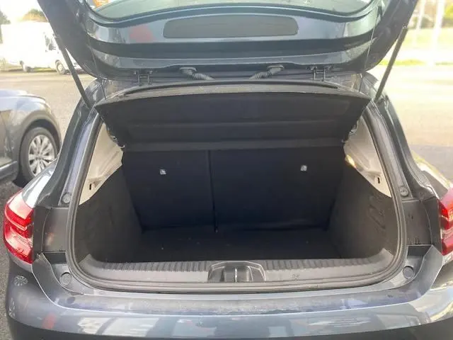 Coffre ouvert vu de l'arrière d'une Renault Clio gris 2021, montrant l'espace de chargement vide et la hayon relevé.