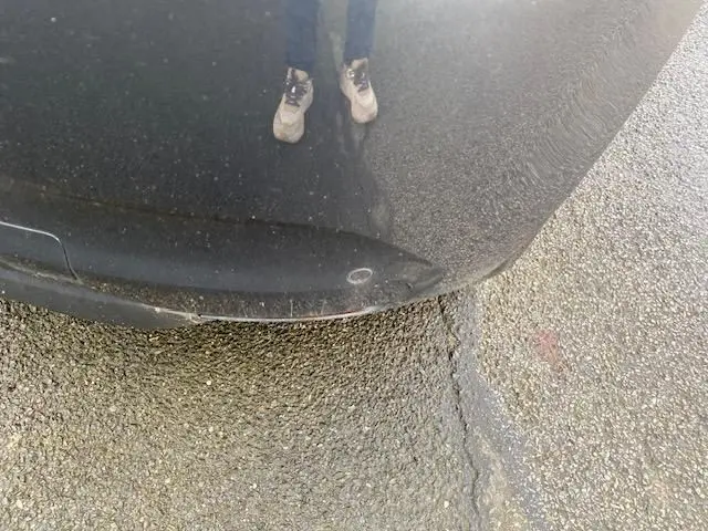 Vue rapprochée du pare-chocs avant gris d'une Renault Clio 1.5 dCi 100 Energy Business, avec reflet au sol.