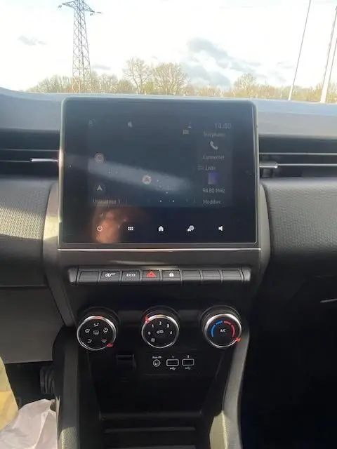 Vue centrale de l'écran tactile et des commandes de climatisation du tableau de bord de la Renault Clio gris 2021.