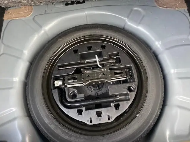 Gros plan sur la roue de secours et les outils de bord dans le coffre d'une Renault Clio gris 2021.