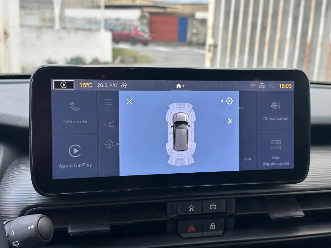 Vue rapprochée de l'écran central du Jeep Avenger noir 2025 affichant l'aide au stationnement et les options connectées.