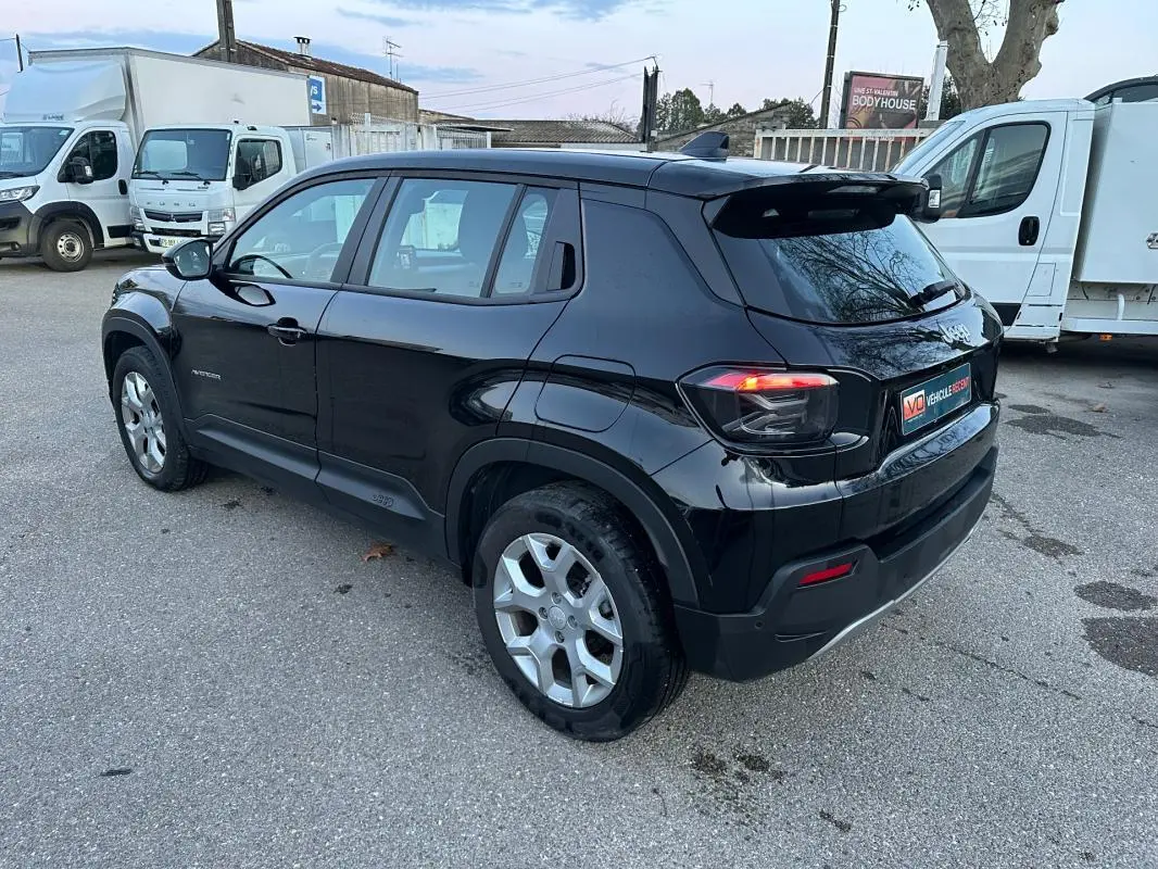 Vue 3/4 arrière droite d'un Jeep Avenger noir 2025 avec jantes alliage 17 pouces et feux arrière LED allumés.
