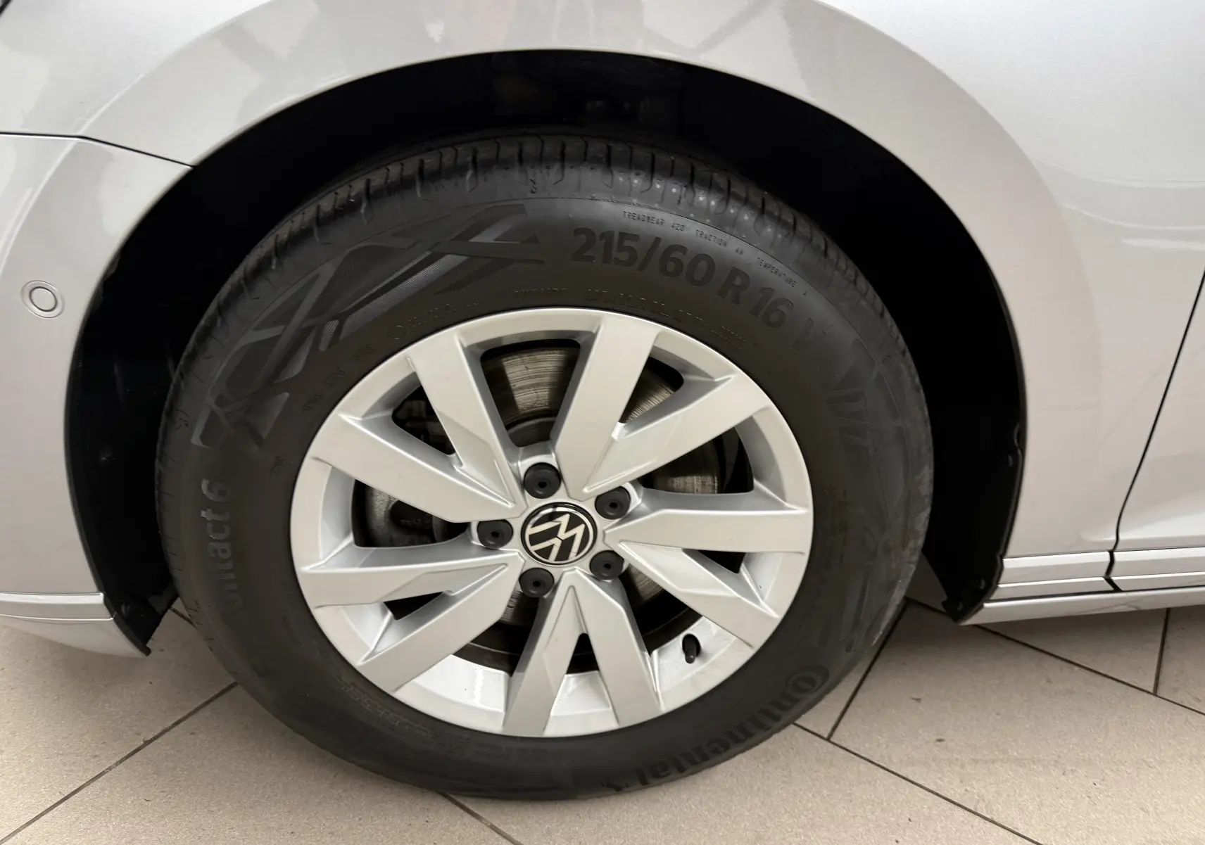 Gros plan sur la roue avant gauche de la Volkswagen Passat SW 2024 gris pyrite avec jante alliage et logo VW central.