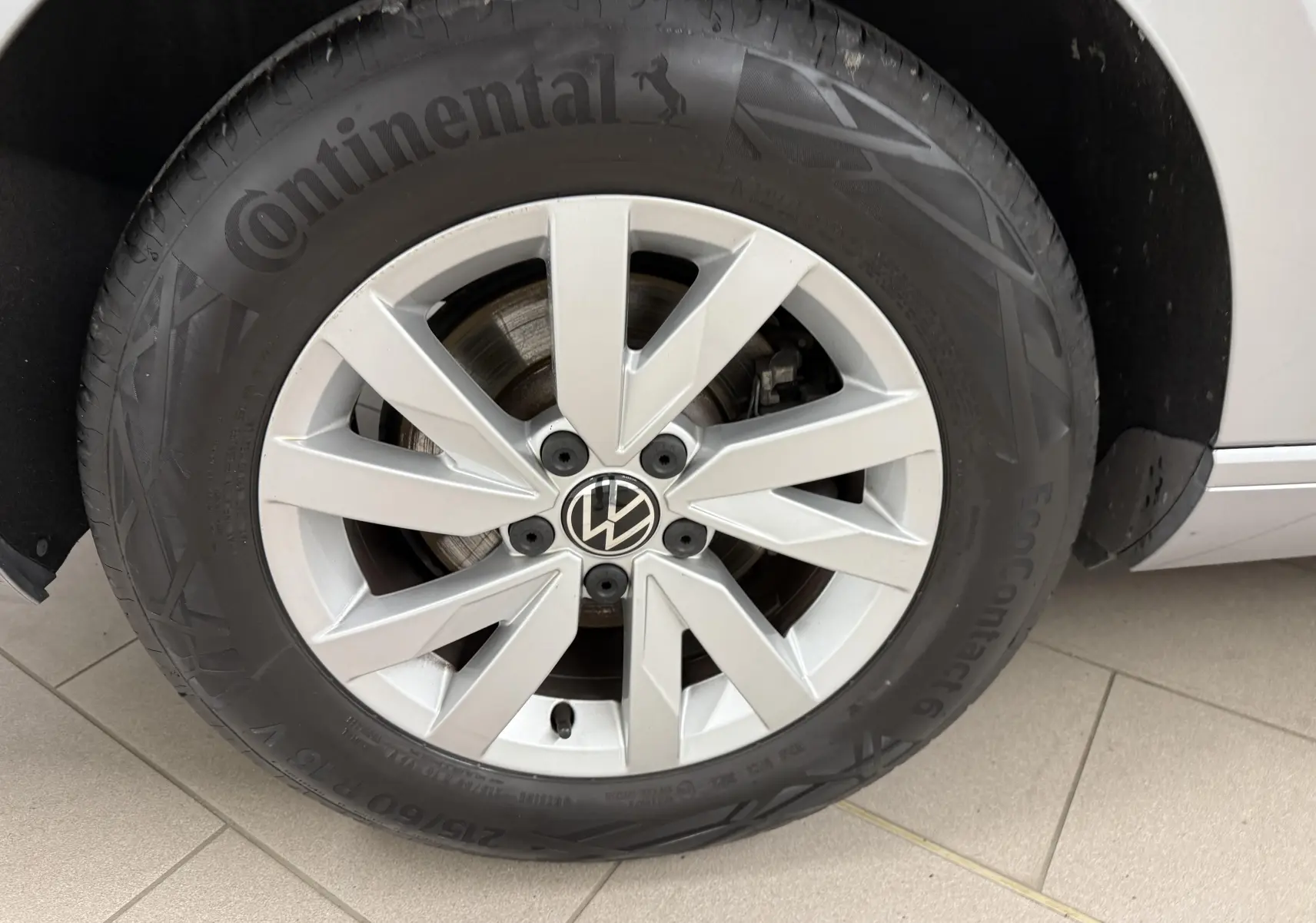 Gros plan sur la roue avant droite de la Volkswagen Passat SW gris pyrite, avec jante alliage et pneu Continental.