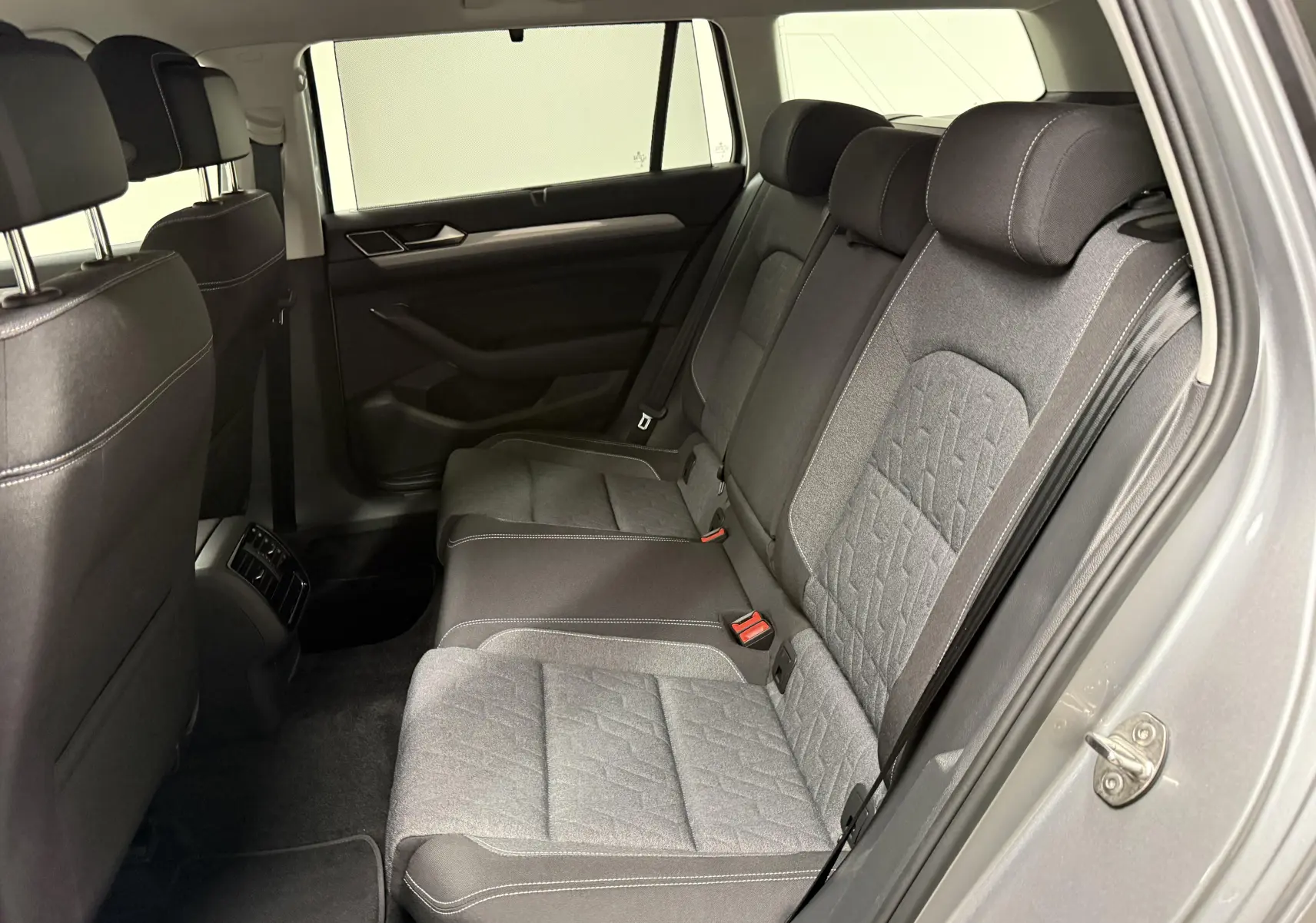 Vue intérieure arrière côté droit de la Volkswagen Passat SW 2.0 TDI 122 DSG7 Business avec sièges tissu gris et noir.
