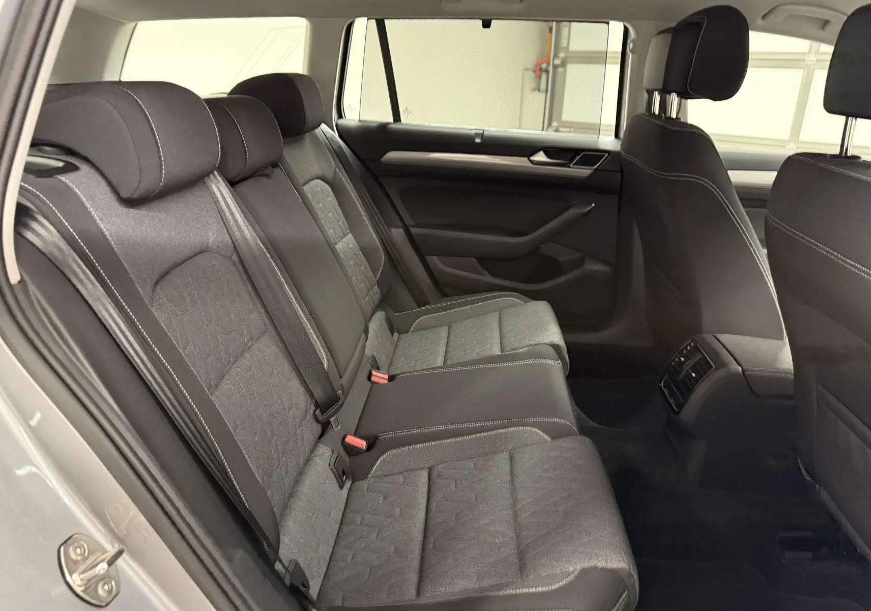 Vue intérieure sur les sièges arrière en tissu gris de la Volkswagen Passat SW 2024, côté gauche ouvert.