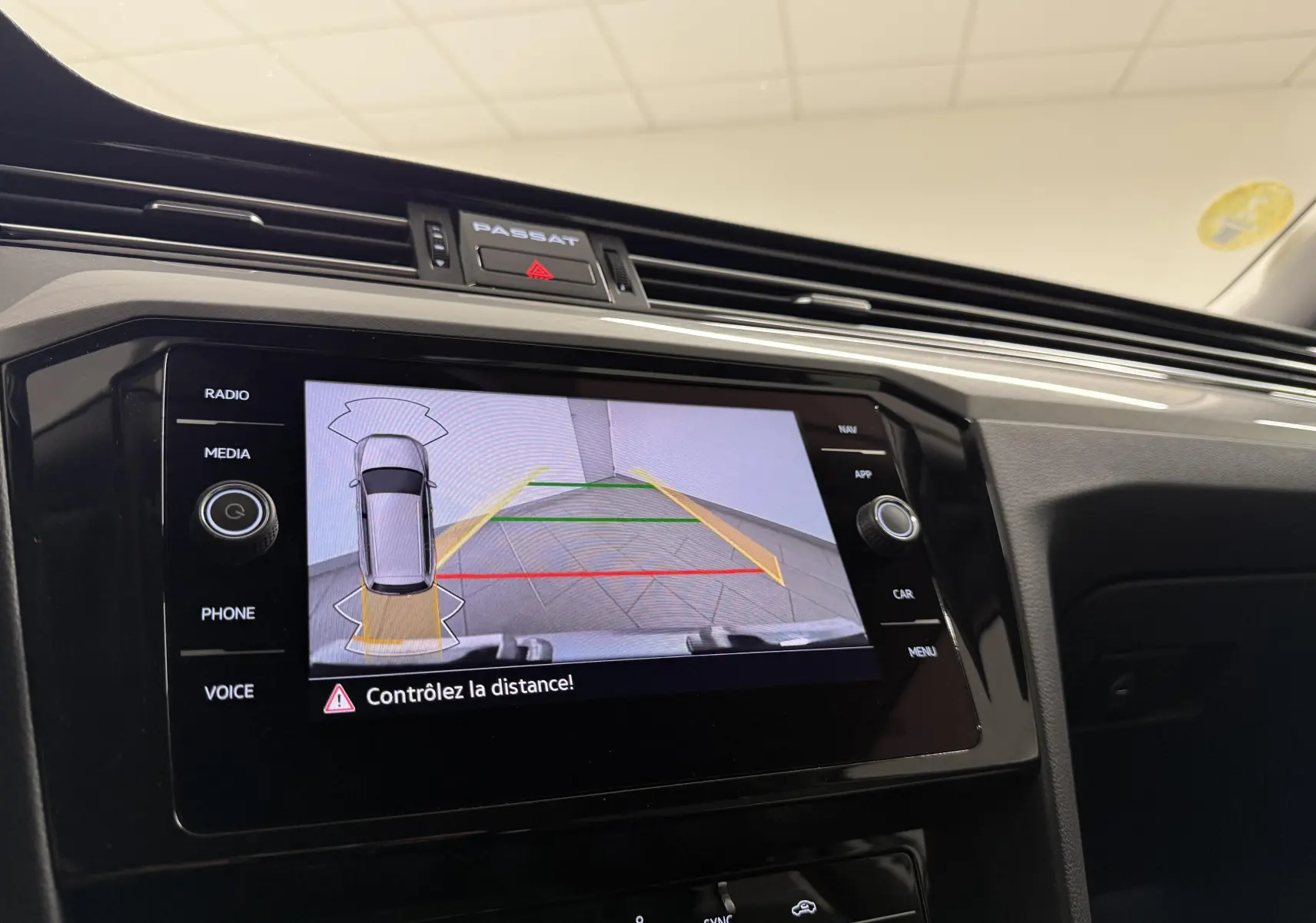Vue rapprochée de l'écran tactile intérieur de la Volkswagen Passat SW gris pyrite montrant l'aide au stationnement arrière.