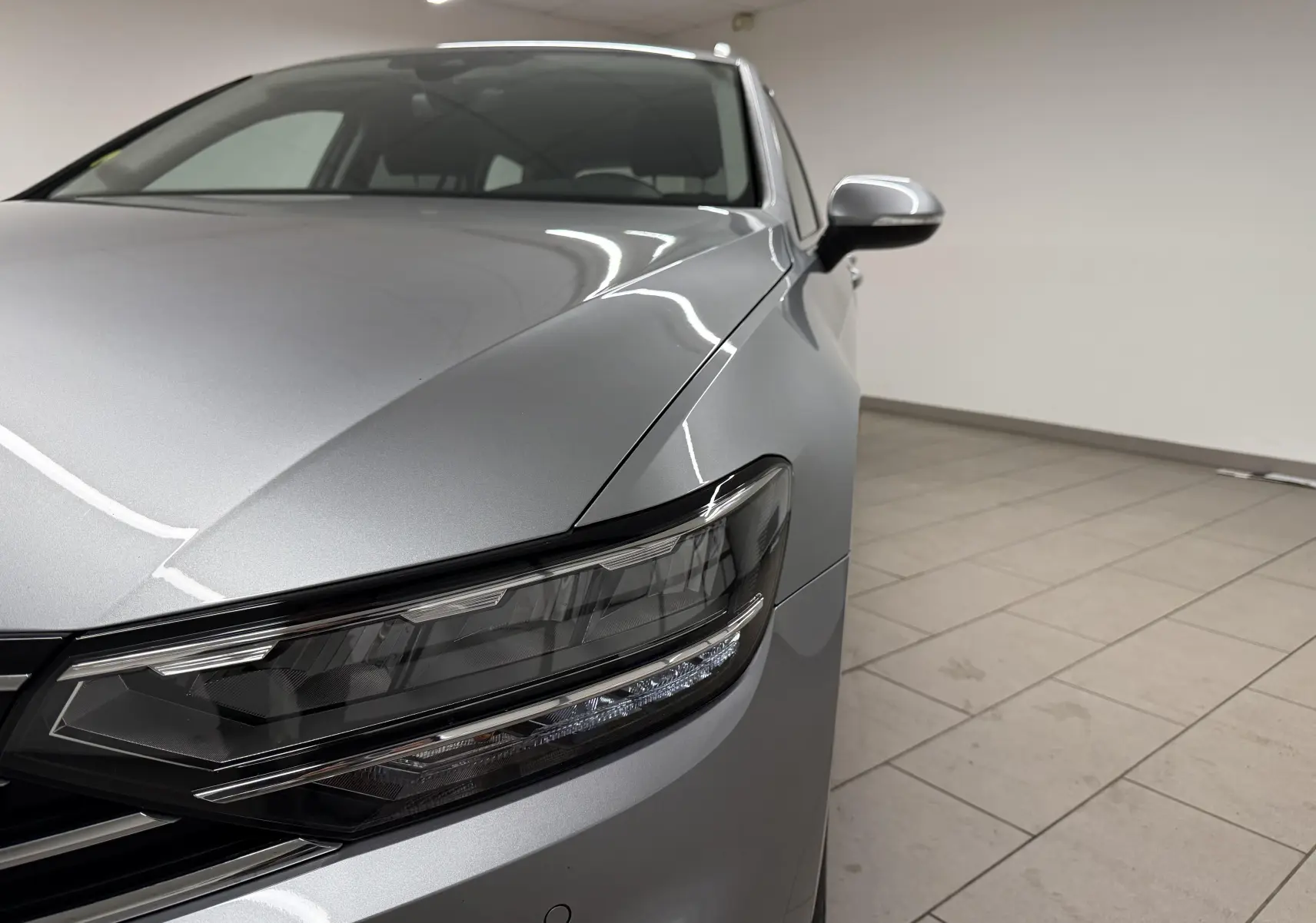 Vue rapprochée 3/4 avant droit de la Volkswagen Passat SW 2.0 TDI Business 2024 en gris pyrite métallisé avec phares LED.