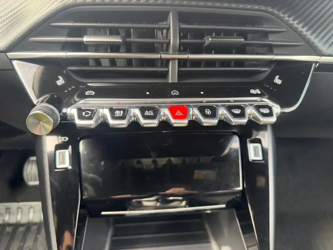 Vue rapprochée du tableau de bord noir du Peugeot 2008 2024 montrant les commandes centrales et les aérateurs.