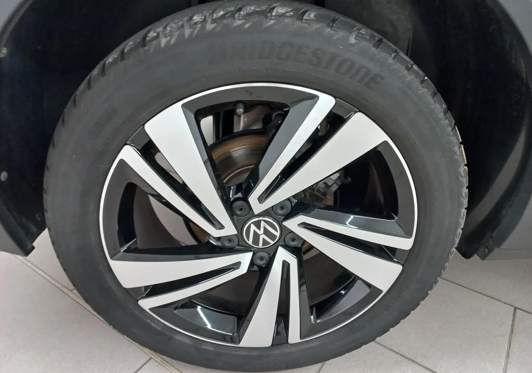 Gros plan sur la jante bicolore noire et argentée du Volkswagen T-Roc 1.5 TSI 2025 Noir Intense nacré.