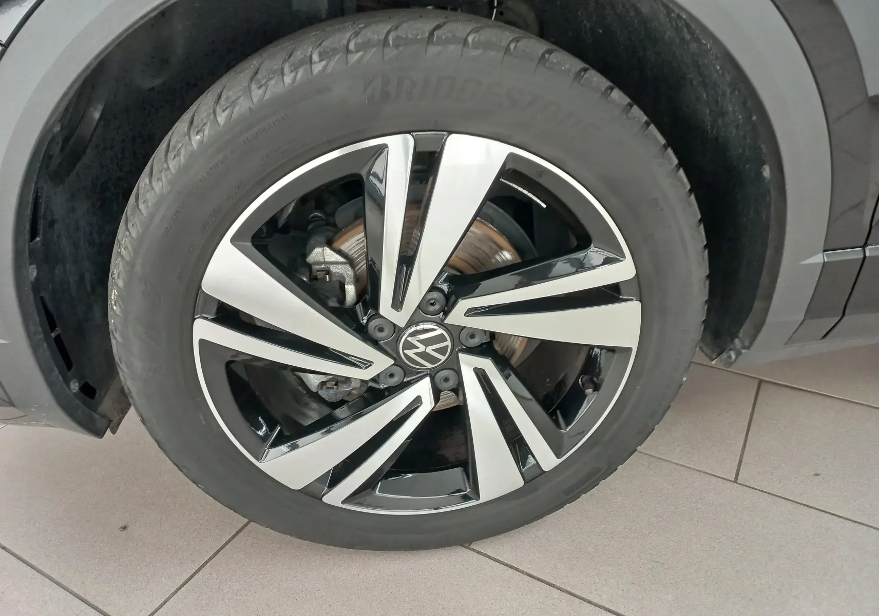 Gros plan sur la roue avant droite du Volkswagen T-Roc 1.5 TSI 150 DSG7 R-Line noir intense nacré avec jante alliage bicolore.