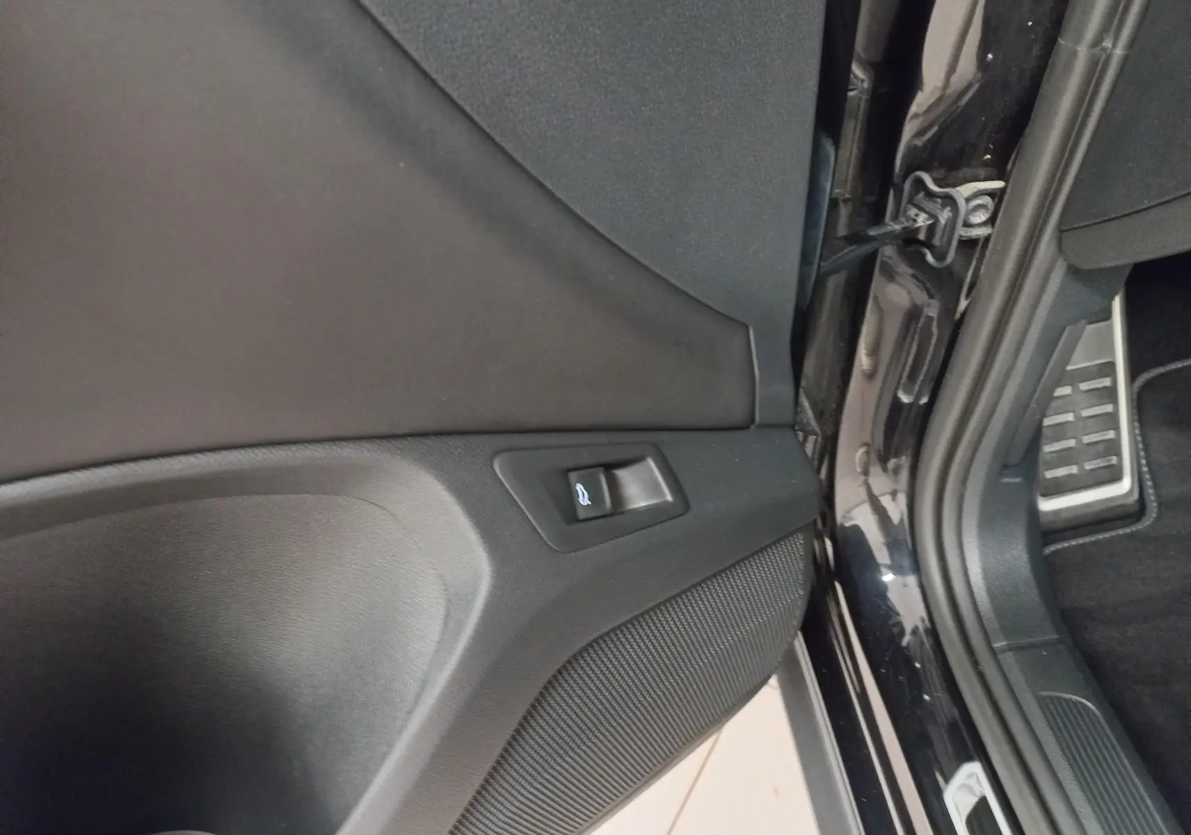 Détail de la portière côté conducteur du Volkswagen T-Roc noir intense nacré avec bouton d'ouverture du coffre.
