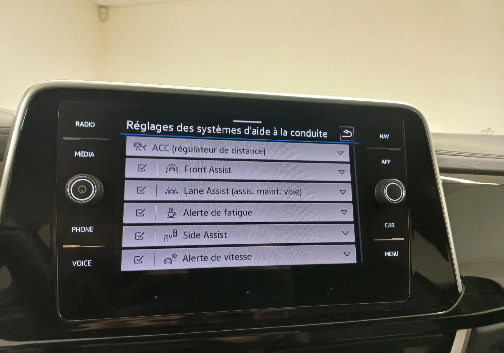 Vue rapprochée de l’écran tactile central du Volkswagen T-Roc 2025 noir intense, affichant les réglages des aides à la conduite.