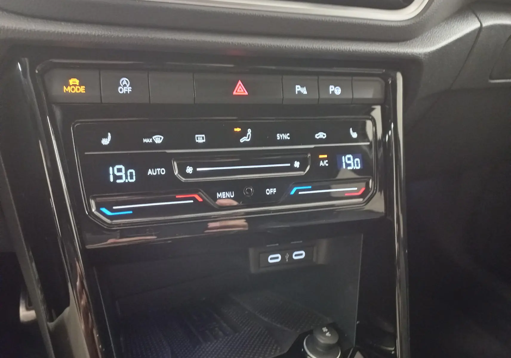 Vue rapprochée de la console centrale du Volkswagen T-Roc 2025 noir intense, affichant la climatisation digitale à 19°C.