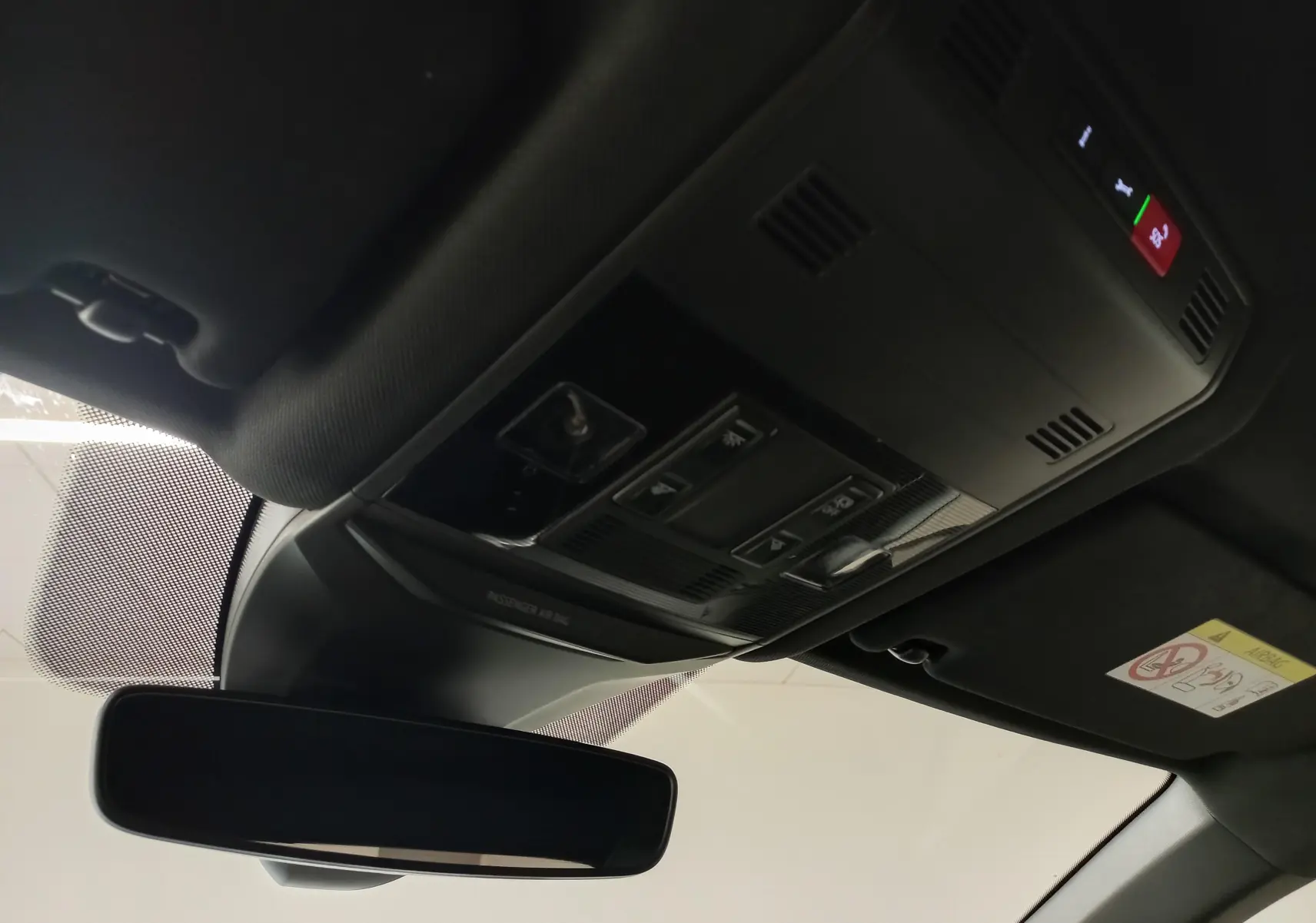 Vue intérieure du plafonnier et rétroviseur d’un Volkswagen T-Roc noir intense nacré, avec commandes intégrées et éclairage d’ambiance.