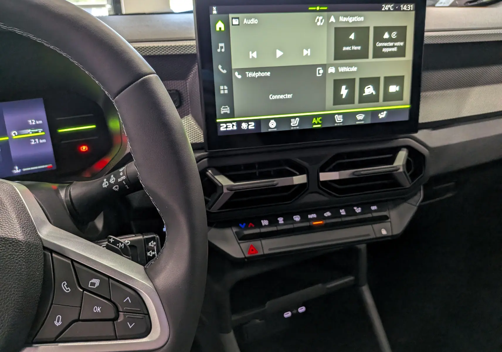Vue intérieure centrée sur le tableau de bord et l'écran tactile du Dacia Duster Hybrid-G 150 CH 4x4, volant partiellement visible.