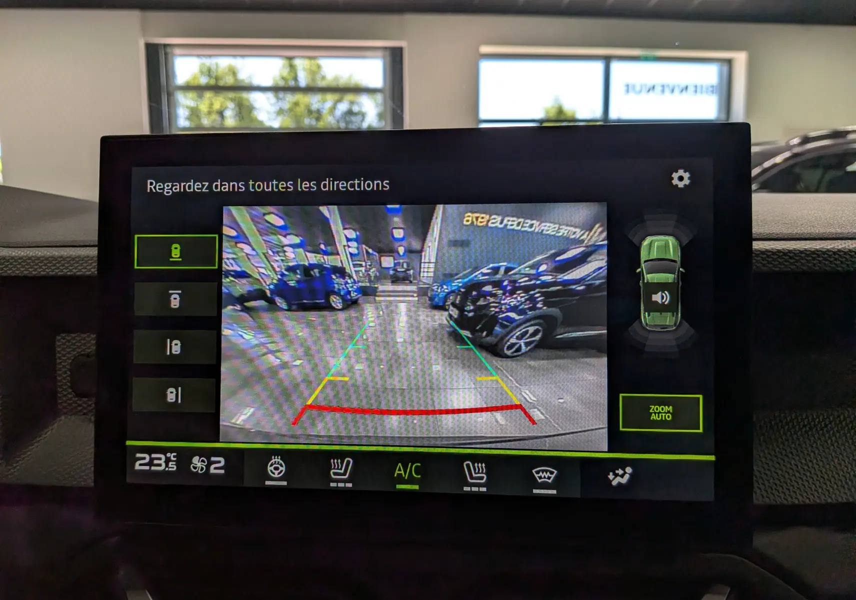 Vue de l'écran multimédia du Dacia Duster gris schiste montrant la caméra de recul avec lignes de guidage colorées.