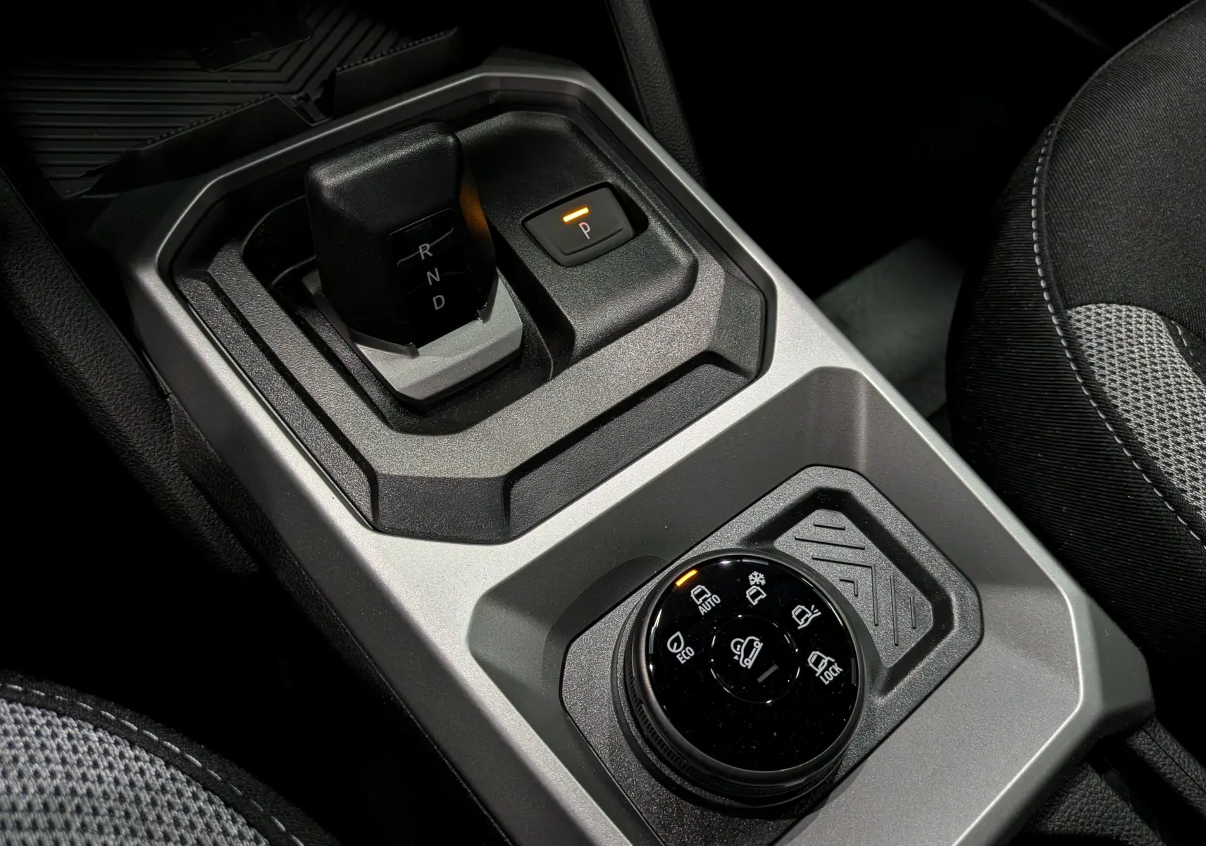 Gros plan sur la console centrale grise du Dacia Duster Hybrid-G 150 CH 4x4 2026, avec levier de vitesses automatique et sélecteur de modes de conduite.
