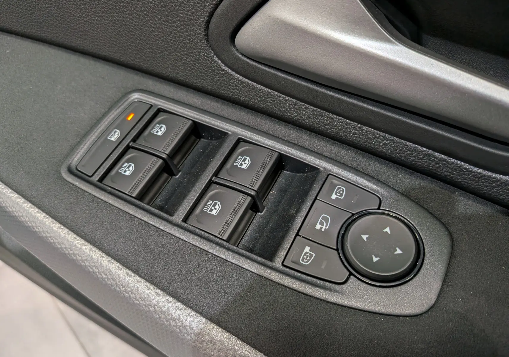 Gros plan sur les commandes de lève-vitres et rétroviseurs côté conducteur du Dacia Duster Hybrid-G gris Schiste.