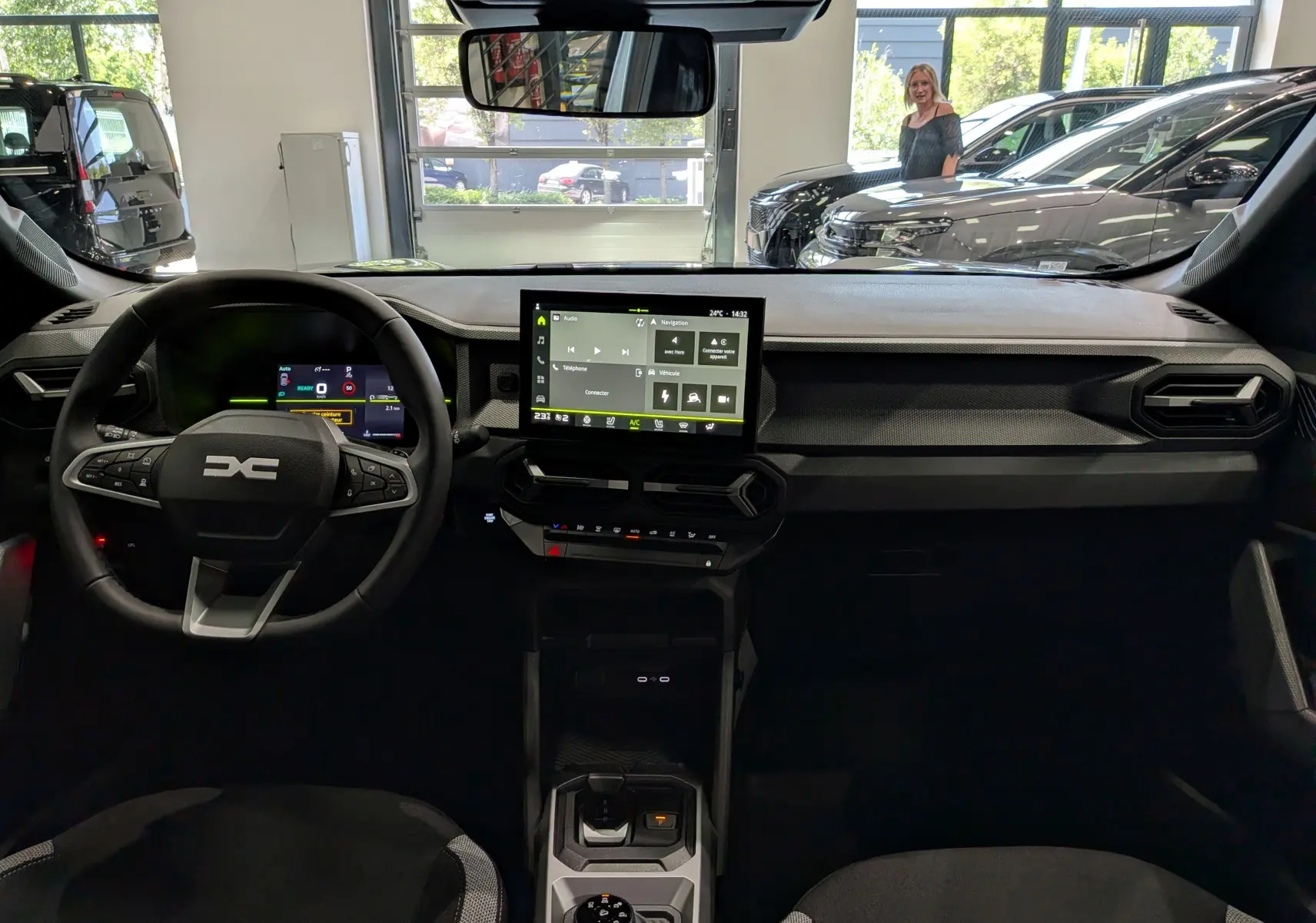Vue intérieure avant du Dacia Duster Hybrid-G 150 CH 4x4 gris, avec tableau de bord numérique et écran tactile central.
