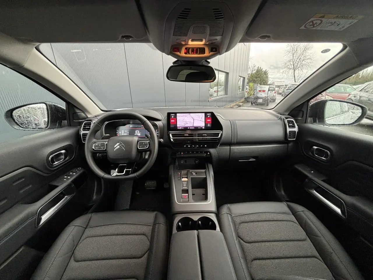 Vue intérieure avant du Citroën C5 Aircross 2025 avec tableau de bord noir, écran tactile central et volant multifonction.