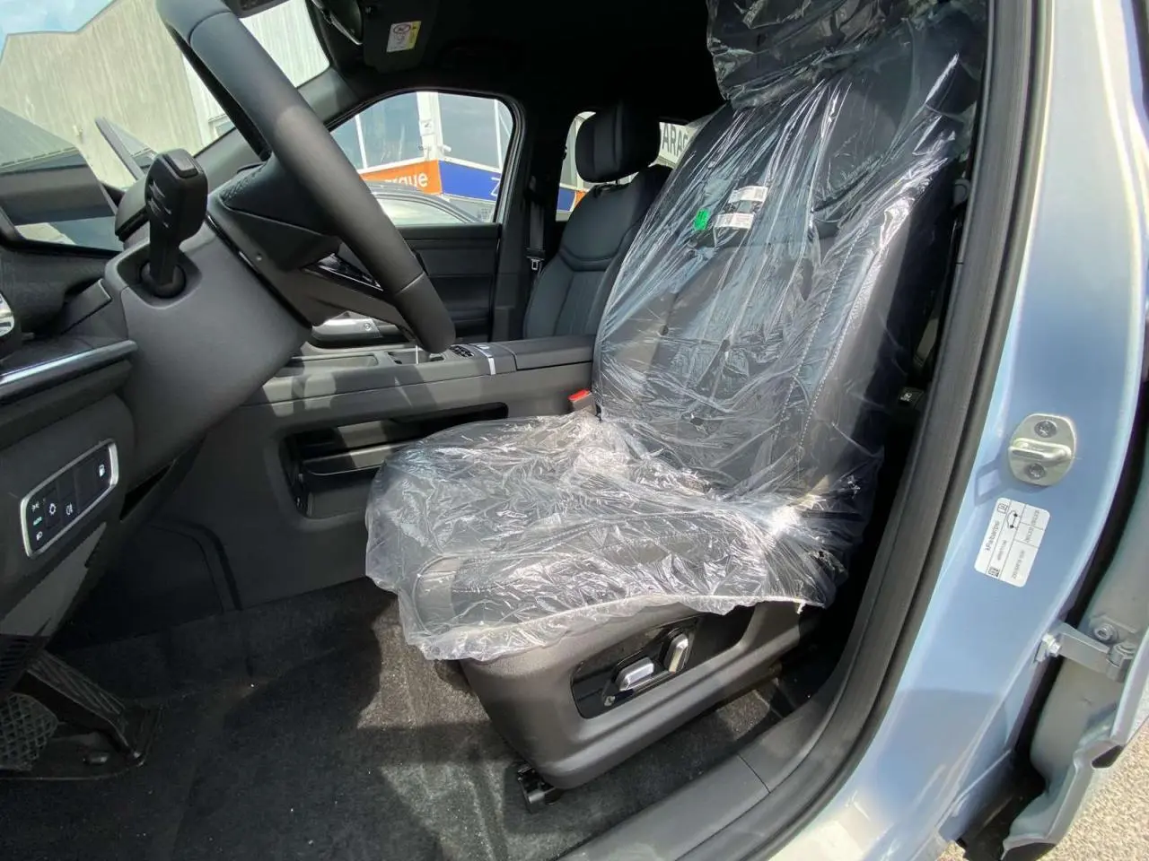 Vue intérieure côté conducteur du JAECOO J7 1.5 SHS-P argent Moonlight, siège avant protégé par film plastique.