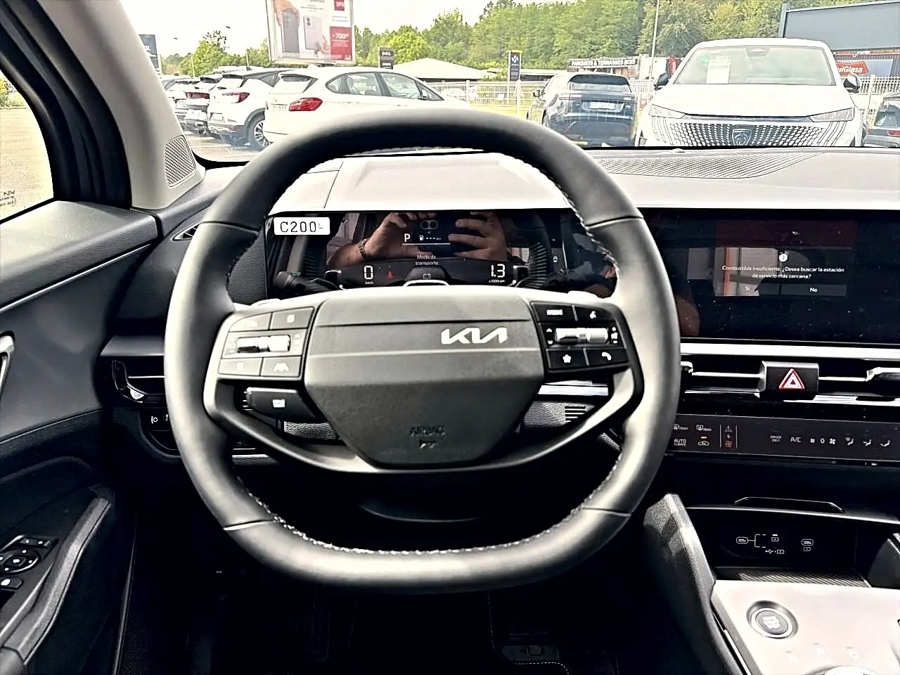 Vue intérieure centrée sur le volant cuir multifonction noir du Kia Sportage 1.6 hybride 239, avec tableau de bord digital.