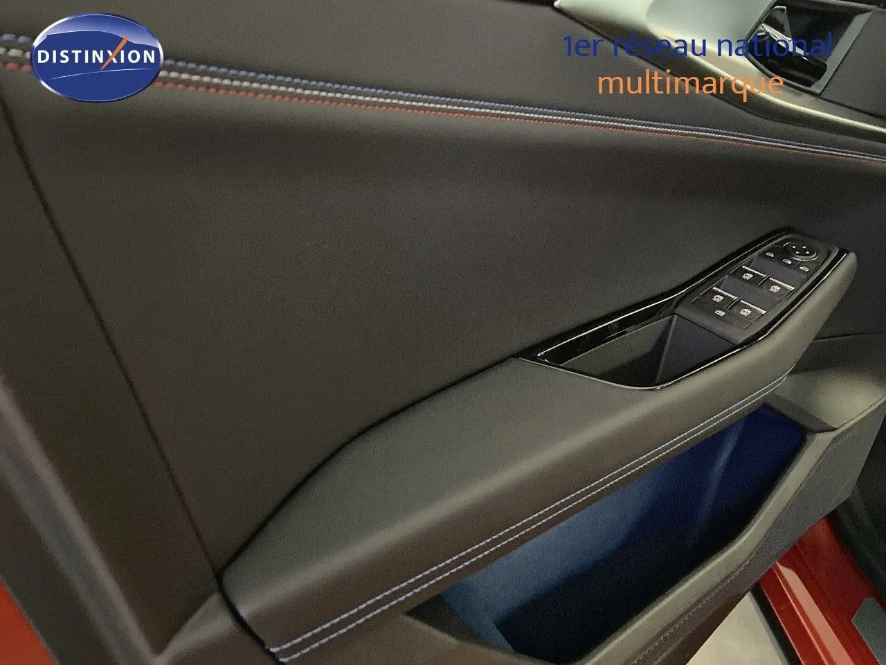 Détail de la porte côté conducteur du Renault Rafale rouge flamme avec surpiqûres bleues et commandes de vitres.