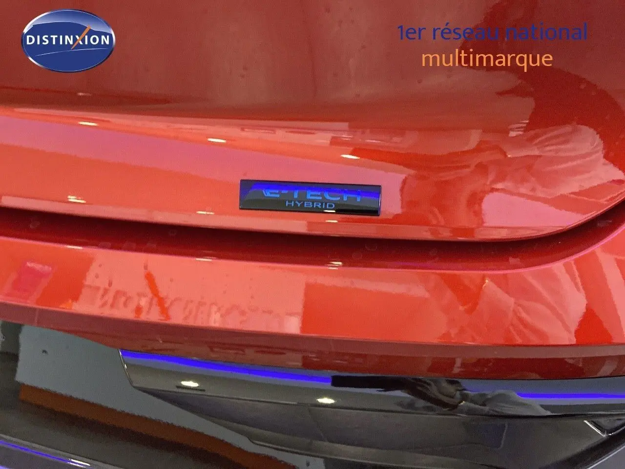 Gros plan sur le badge E-TECH Hybrid à l'arrière d'une Renault Rafale rouge flamme métal 2024.