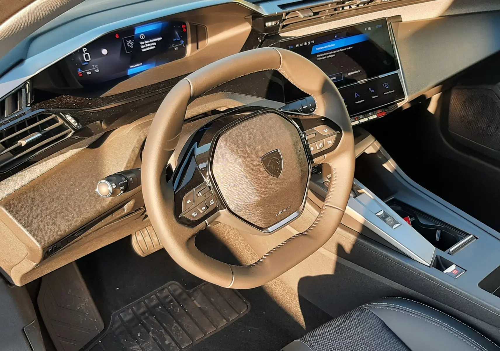 Intérieur Peugeot 308 2025 vue côté conducteur, volant compact, tableau de bord numérique et écran tactile central.