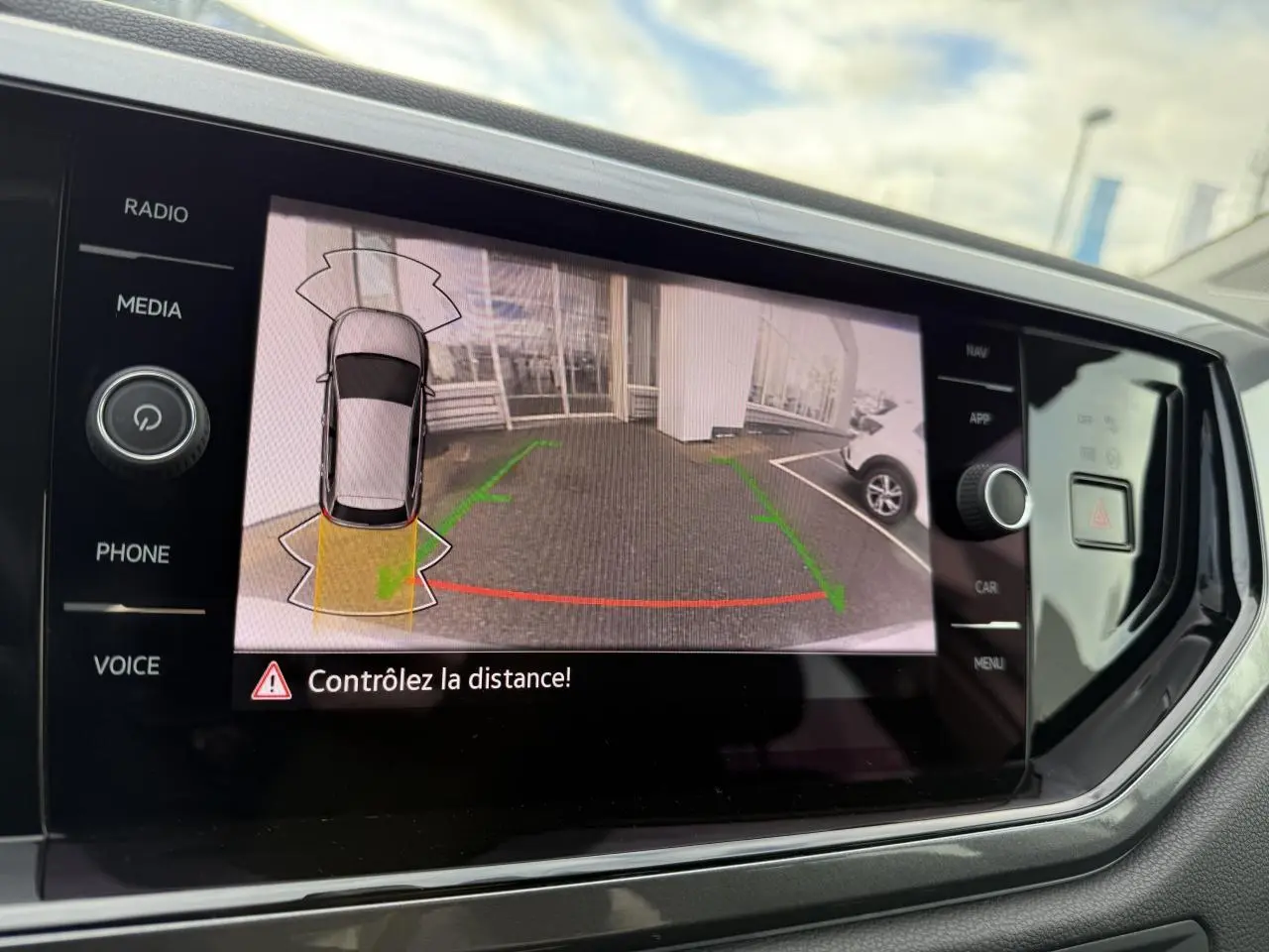 Écran tactile intérieur montrant la caméra de recul active d'une Volkswagen Polo argent métallisé en stationnement.