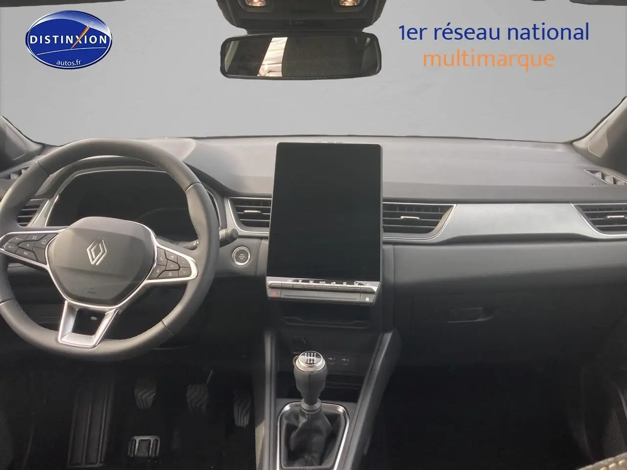 Vue frontale de l'intérieur du Renault Captur bleu iron 2025, avec volant multifonction et écran tactile vertical.