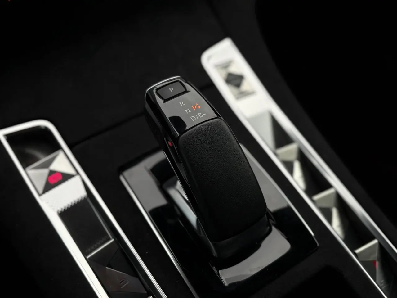 Le levier de vitesses noir brillant de la DS7 1.6 E-Tense 225 BVA vu en gros plan sur la console centrale.