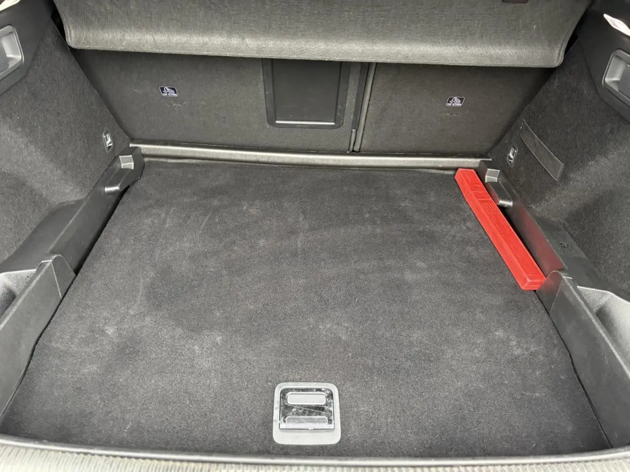 Coffre spacieux du DS7 1.6 E-Tense gris laqué, vue intérieure montrant le tapis noir et un triangle de sécurité rouge.