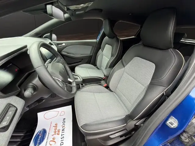 Intérieur avant droit de la Renault Clio V E-Tech bleu Iron, sièges textile gris/noir avec surpiqûres cuivre visibles.