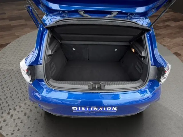 Coffre ouvert vu de l'arrière d'une Renault Clio V bleu Iron, montrant l'espace de chargement vide et les feux arrière.