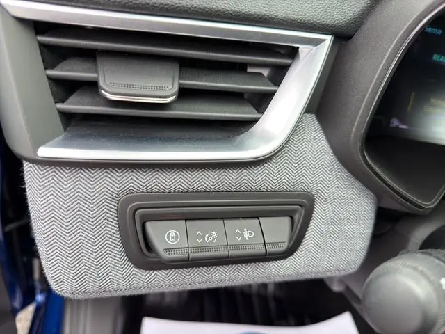 Détail intérieur côté gauche de la planche de bord avec commandes d’éclairage et tissu gris à chevrons sur Renault Clio V Bleu Iron.