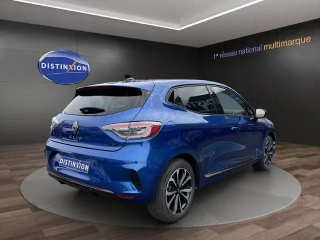 Renault Clio V E-Tech hybride bleu Iron vue 3/4 arrière droit, jantes alliage noires et vitres surteintées.