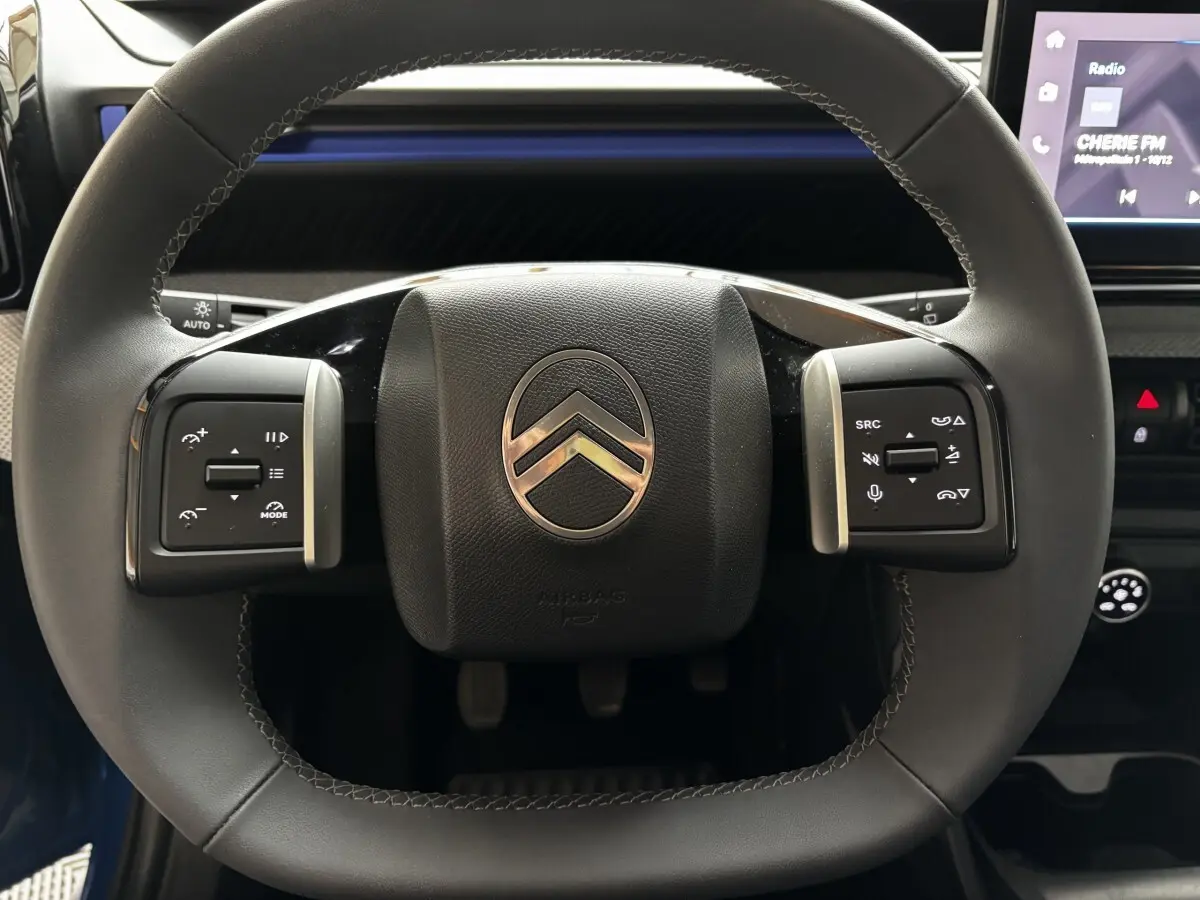 Gros plan sur le volant cuir noir de la Citroën C3 100 BVM PLUS 2025 avec commandes multifonctions et écran tactile visible.