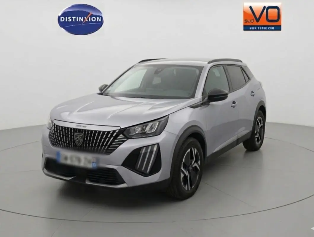 Peugeot 2008 Hybrid gris en 3/4 avant droit, avec barres de toit et jantes alliage 17 pouces visibles.