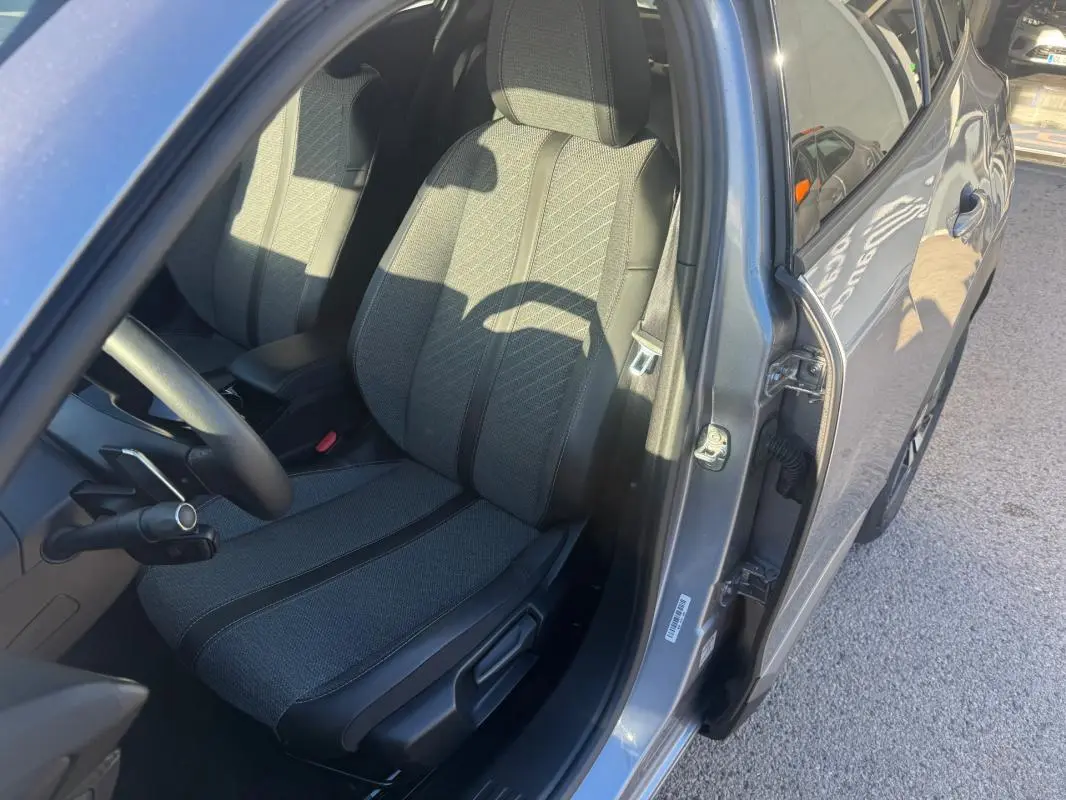 Vue côté gauche intérieur du siège conducteur gris du Peugeot 2008 Hybrid 136 e-DCS6 Allure 2024 avec porte ouverte.