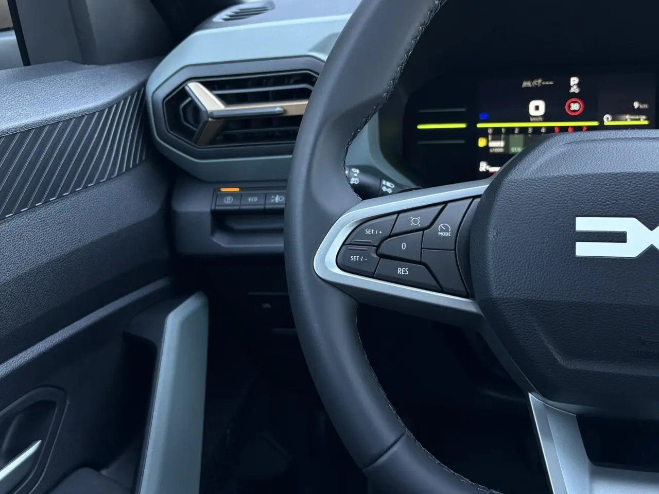 Vue rapprochée du volant et tableau de bord digital du Dacia Duster 2026, intérieur noir avec commandes au volant.