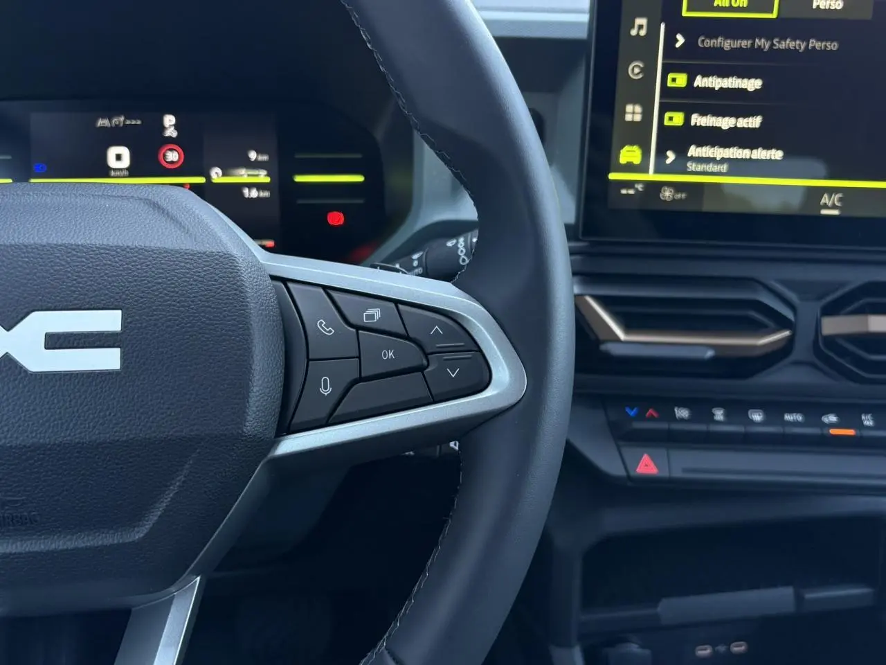 Vue rapprochée du volant et du tableau de bord digital du Dacia Duster gris, avec commandes au volant et écran tactile.