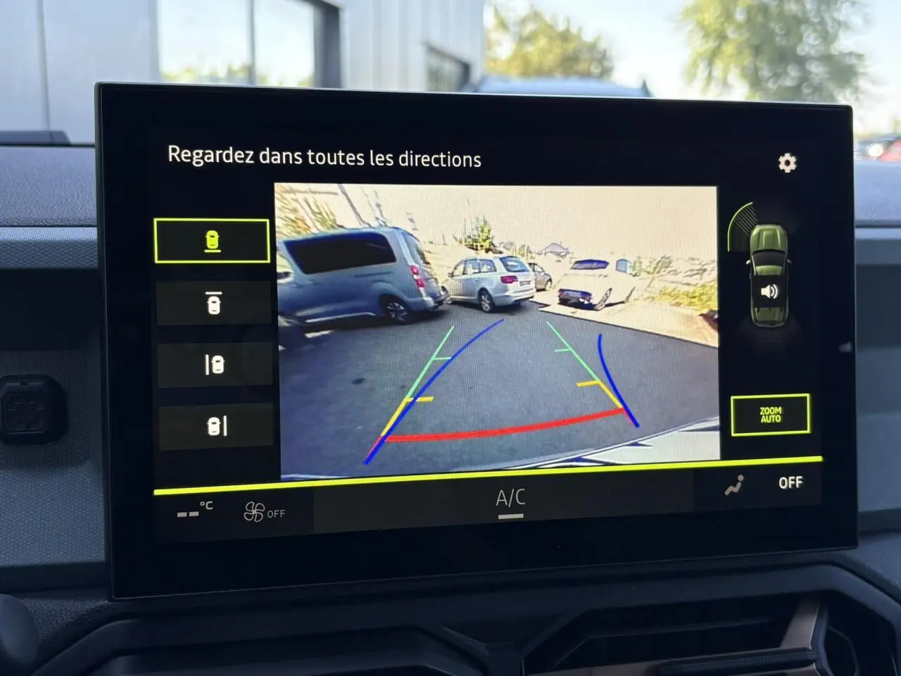 Écran central tactile montrant la caméra multivues du Dacia Duster gris schiste en marche arrière, avec guidage coloré.