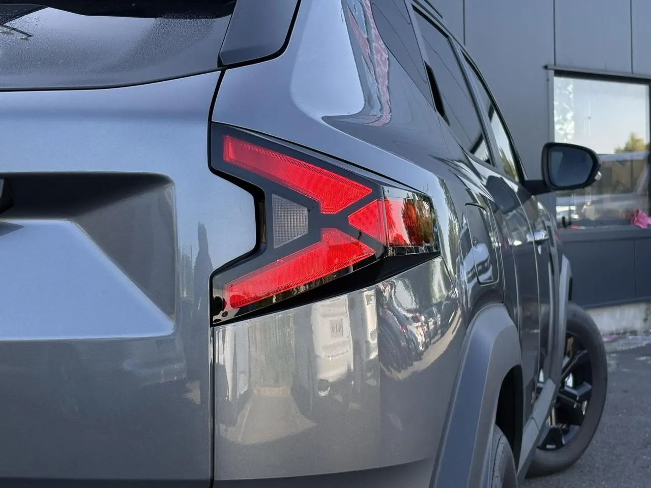 Gros plan sur le feu arrière droit du Dacia Duster 2026 gris schiste, mettant en valeur la finition moderne et les jantes noires.