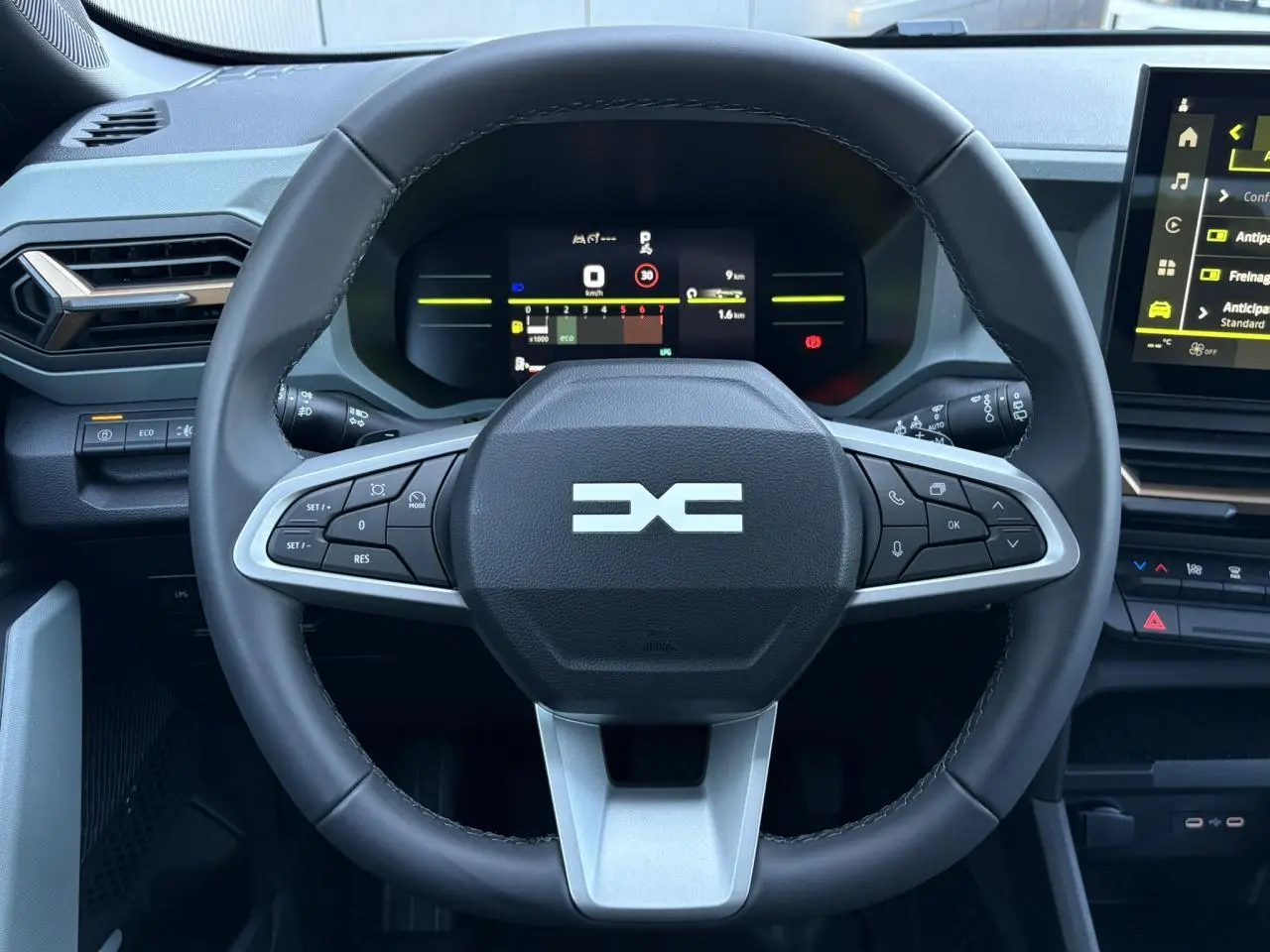 Vue rapprochée du volant noir du Dacia Duster 2026 avec tableau de bord digital et écran tactile central.
