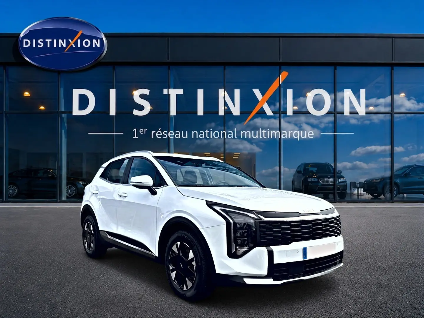 KIA Sportage 1.6 hybride blanc en 3/4 avant droit, avec calandre noire et jantes alu 17 pouces devant showroom Distinxion.