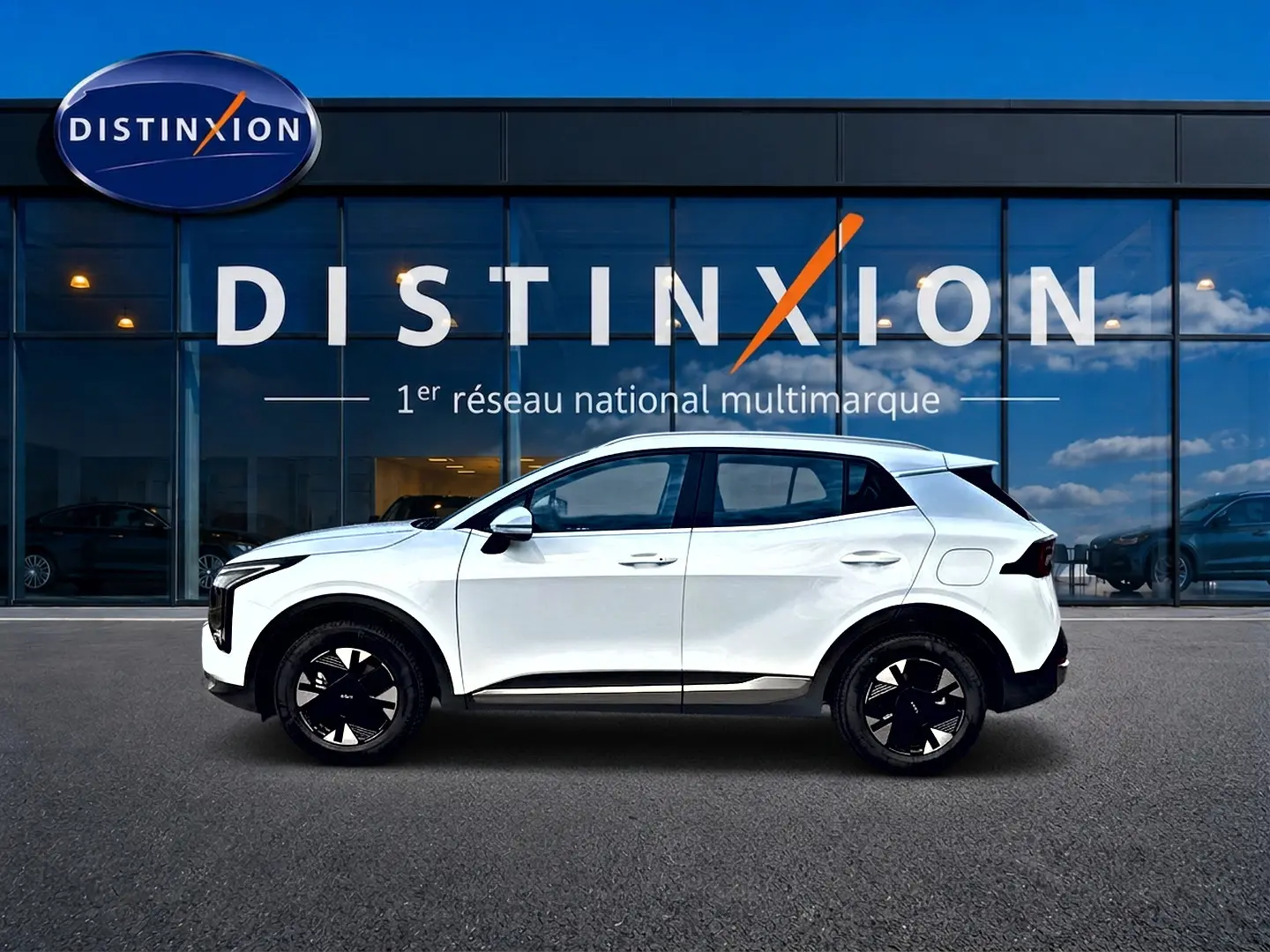 Vue latérale gauche d'un KIA Sportage blanc 2026 avec jantes alu noires et détails noirs contrastants.