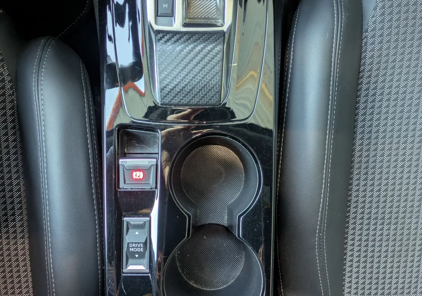 Vue plongeante sur la console centrale noire brillante du Peugeot 2008 GT, avec levier de vitesses automatique et porte-gobelets.